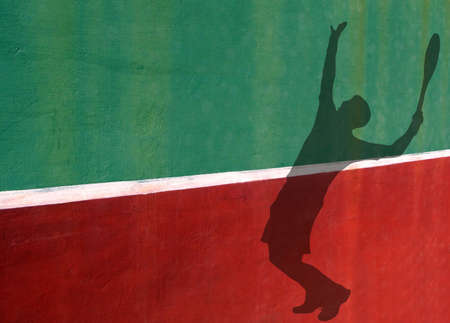 Silhouette of Tennis Player Serving Against a Practice Wallの写真素材