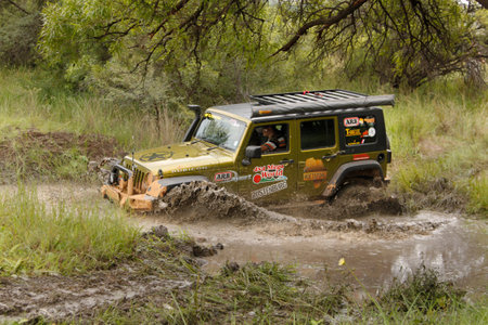 BAFOKENG - MARCH 8: Gecko Pearl Green Jeep Wrangler Rubicon crossing muddy pond obstacle at Leroleng 4x4 track on March 8, 2014 in Bafokeng, Rustenburg, South Africaのeditorial素材