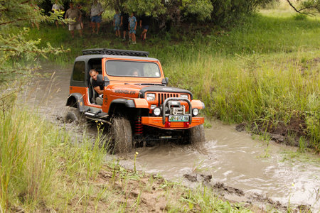 BAFOKENG - MARCH 8: Crush Beige Jeep Wrangler Off-Roader V8 crossing muddy pond obstacle at Leroleng 4x4 track on March 8, 2014 in Bafokeng, Rustenburg, South Africaのeditorial素材
