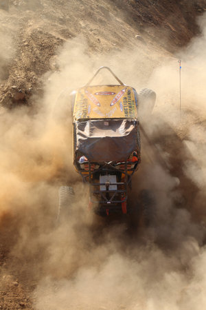 Rustenburg, South Africa - JUNE 17, 2017: National Extreme Modified 4x4 Vehicle Championship. Yellow Car powering up steep hill, kicking up sand and dust.のeditorial素材