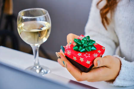 Close up. Holidays christmas winter concept. young woman with laptop computer at home and holding a red gift in his hand.の写真素材