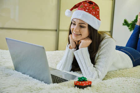 Holidays christmas interior winter concept. young woman in cozy bedroom with laptop computer lying on bed at home. Close upの写真素材