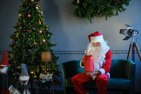 Portret Santa Claus opens magic glowing gift box and looks inside, bright light shines from box.の写真素材