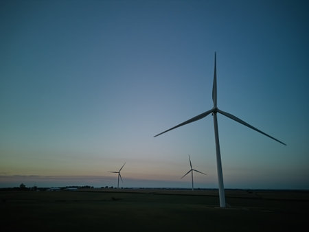 Aerial wide view of a silhouette many wind turbine standing in a wheat field at night time.の写真素材