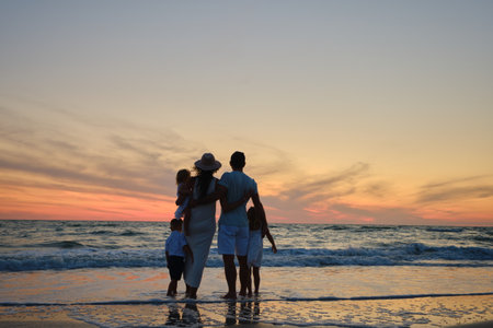 Silhouette A hugging family on summer holidays enjoys the beautiful sunset over the seaの写真素材