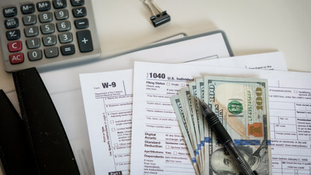 Close up of a 1040 and W9 individual tax form are placed on desk of American citizen. Top shotの写真素材