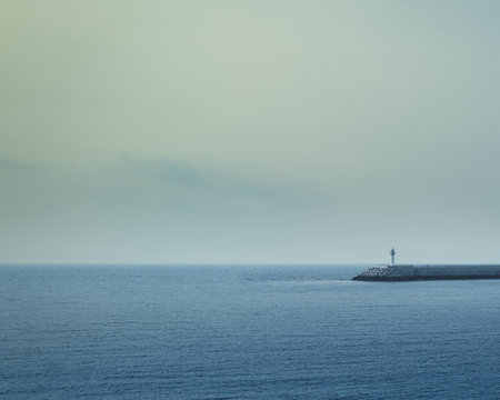 Lighthouse in the middle of the sea with a cloudy sky.