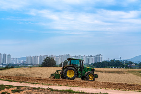 Tractor working in the rice field with blue sky and cloud backgroundの写真素材