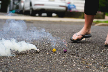 Three smoke bombs in the street smoking near a woman's feetの写真素材