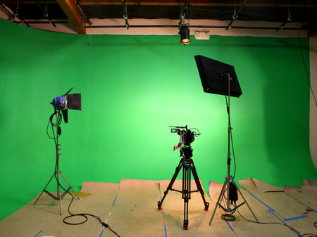 An illuminated green screen sound stage with two lights and a motion picture camera set upの写真素材