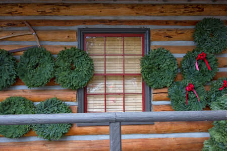 Christmas Wreaths on Log Caban with Red Window Frameの写真素材