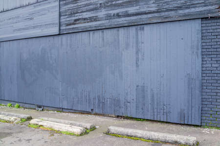 Purpl/grey/black rundown brick and wood panel wal boardered by parking lotlの写真素材