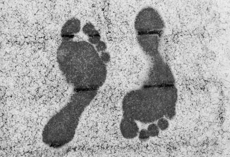 Two opposite barefoot footprints on snow at winterの写真素材