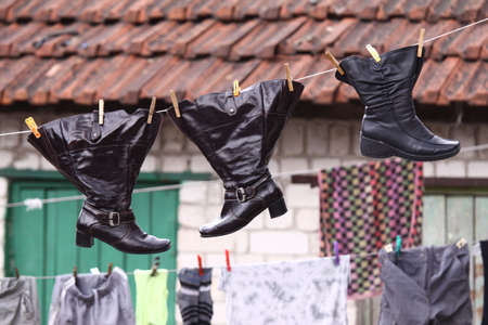 Wet shoes hanging on the clothesline along with other laundryの写真素材