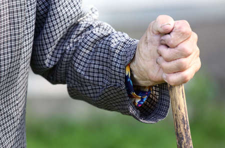 Old tired woman's hand holding wooden stickの写真素材