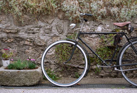 Decorative vintage bicycle and stone flower pot against stone wallの写真素材