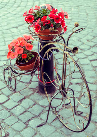 Picture with retro looking effect of decorative metal bicycle with pots of colorful flowersの写真素材