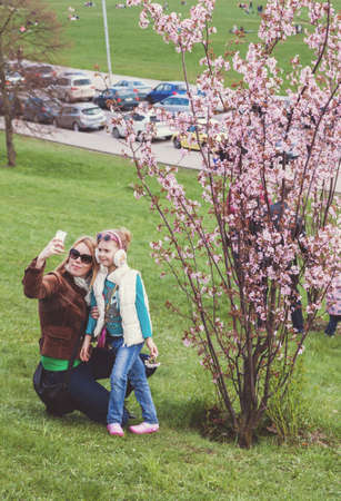 VILNIUS, LITHUANIA - APRIL 25, 2015: Mother taking selfie with her little daughter in front of blossoming cherry tree in Vilnius, Lithuania.のeditorial素材