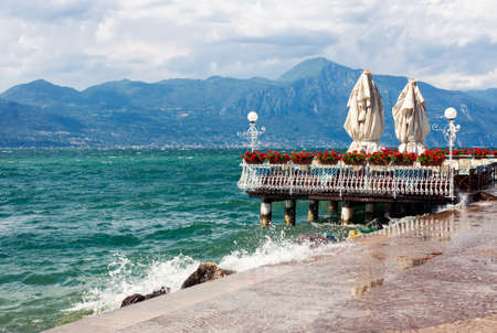 Stormy Garda lake with promenade and closed restaurant in Torri del Benaco, Italyの写真素材