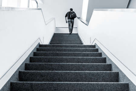 Colorized picture of one man walking upstairs on staircase indoorsの写真素材
