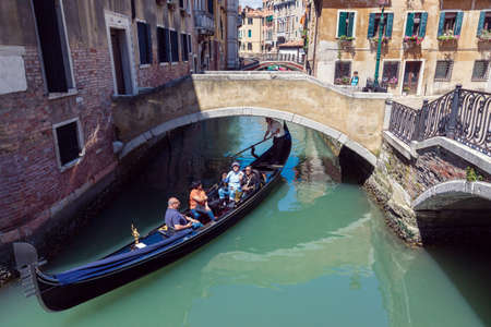 VENICE, ITALY - MAY 27, 2015: Tourists on a gondola on sunny day in Venice, Italy.のeditorial素材