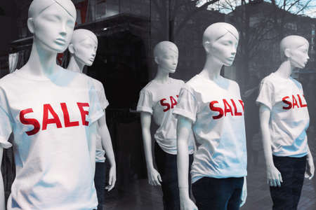 Window display with five mannequins wearing t-shirts with text Saleの写真素材