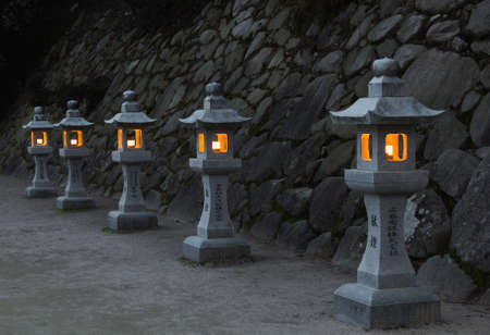 Traditional japanese stone lanterns burning in the eveningの写真素材
