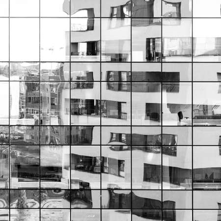 Modern architecture building reflected on glass facade of another building. Abstract looking black and white backgroundの写真素材