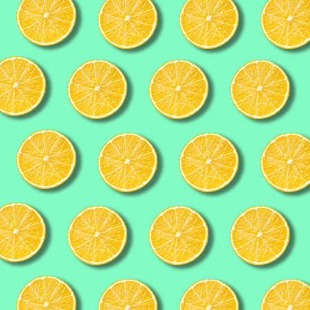Lemon slices pattern on light vibrant green color background. Minimal flat lay food textureの写真素材