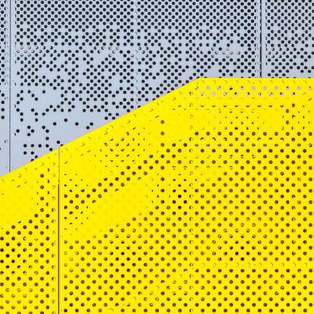 Grey and yellow perforated industrial metal background, abstract dotted textureの写真素材