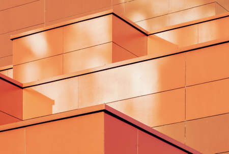 Orange colored geometric background of metal building facade. Abstract architectural shapes and linesの写真素材