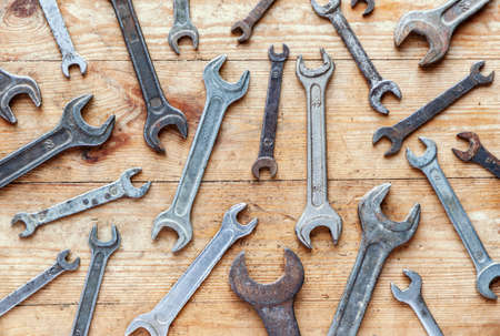 Old rusty wrenches on wooden background, flat lay top view industrial wallpaperの写真素材
