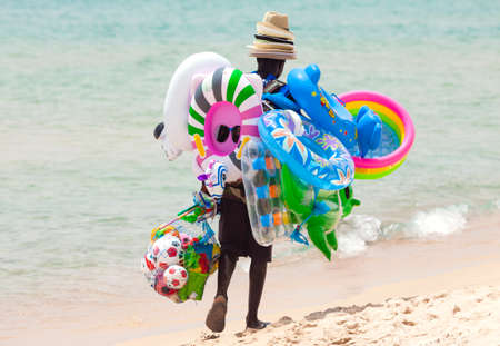 Santa Margherita di Pula, Italy - July 05, 2016: Candid picture of black unemployed man walking on the beach on hot summer day and selling toys and beach items in Santa Margherita di Pula in Sardinia, Italyのeditorial素材