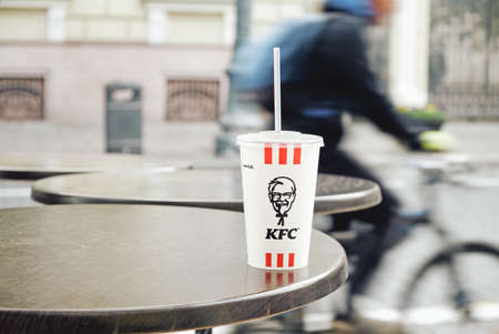 Vilnius, Lithuania - October 12, 2020: KFC Kentucky Fried Chicken soda paper cup with plastic lid and drinking straw abandoned on restaurant table outdoorsのeditorial素材