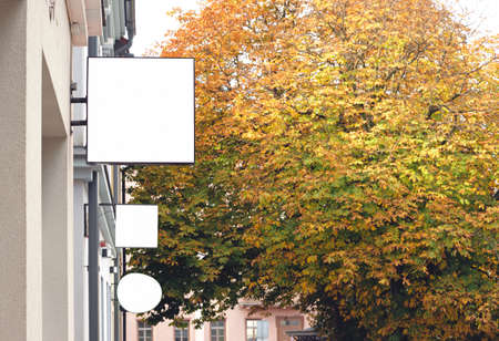 Three empty outdoor wall signboards hanging in autumn city, blank business signage with copy space to add text or logoの写真素材