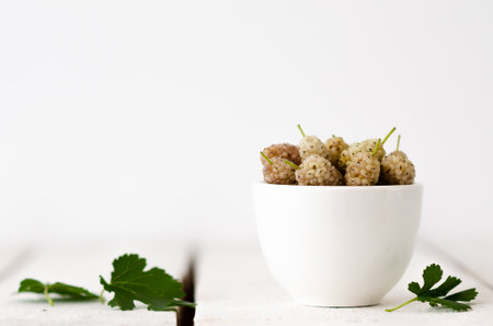 White blackberries in a white bowl with blackberry leaves.の写真素材