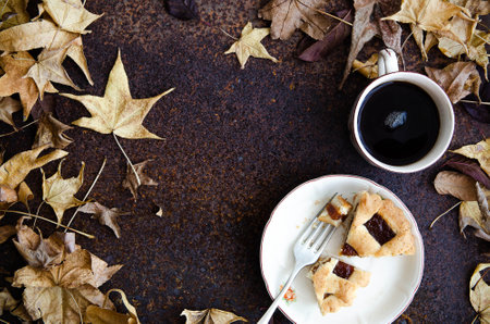 Pieces of pastafrola on a white plate with a fork and a cup of tea, with tree leaves.の写真素材