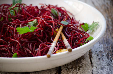 Beetroot salad with parsley and chopsticks, on a wooden backdrop.の写真素材