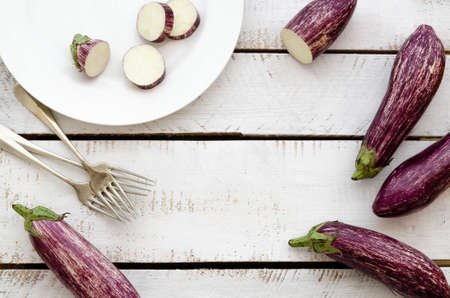 Whole and sliced aubergines listed de Gandia in a white plate with forks, on white backdrops.の写真素材