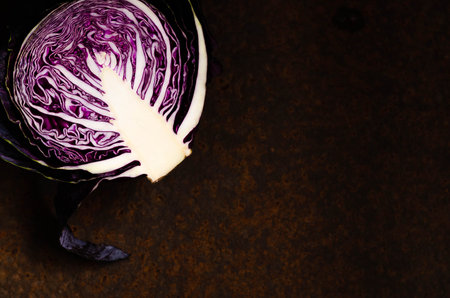 Half of a red cabbage on a dark backdrop.
