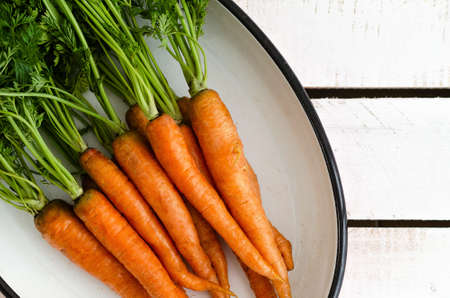 Carrots in a white tray on a white wooden backdrop. Top view.の写真素材
