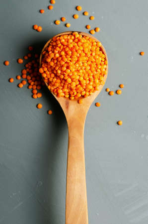 Red lentils in a wooden spoon on light blue backdrop.の写真素材