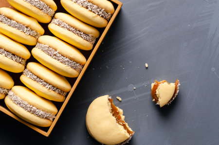 Cornstarch alfajores with milk caramel and coconut in a wooden box on a light blue background.の写真素材
