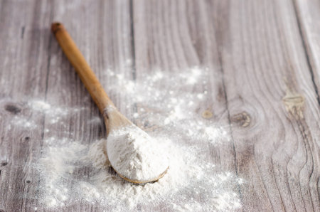 A spoonful of white flour on wooden backdrop. Copyspace.