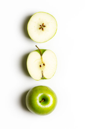 Green whole and sliced apples on white background with copy space.