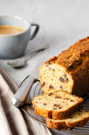 A banana bread with chocolate chips, some bananas and a blue napkin, on gray background.の写真素材