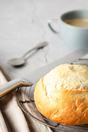 A cup of coffee and a loaf of bread with a brown napkin on gray background.の写真素材