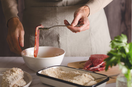 Close up of female hands cooking Argentine milanesas in the kitchen at home.の写真素材