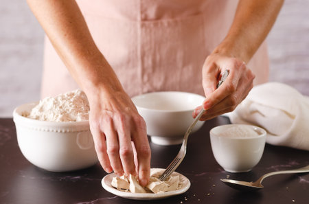 Young woman in a pink apron starting to knead with flour and yeast. Cooking process.の写真素材