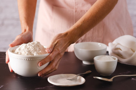 Close-up of female hands holding a bowl of flour ready to knead. Cooking process.の写真素材